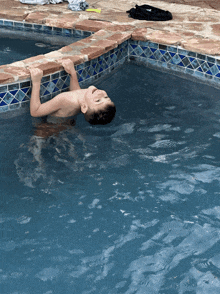 a boy is swimming in a pool with his head above the water