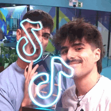 two men standing next to each other holding a neon sign that says s and j