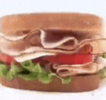 a sandwich with lettuce tomato and turkey on a white surface