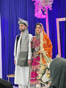 a man and a woman are standing in front of a blue curtain