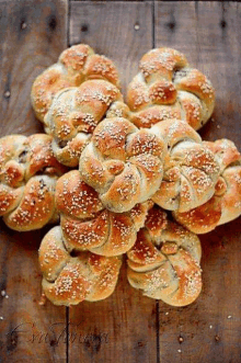 a bunch of bread with sesame seeds on them are sitting on a wooden table .