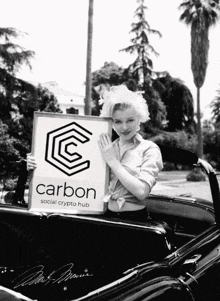 a black and white photo of a woman holding a sign that says carbon