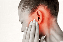 a woman holds her hand to her ear with a red spot on her face