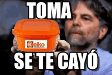 a man with a beard is holding an orange container with a keiko logo on it .