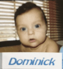 a baby with the name dominick written on a sign