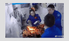 a group of people in blue uniforms are cooking on a grill