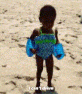 a little girl is standing on a beach holding a pair of floaties and saying i can 't drive