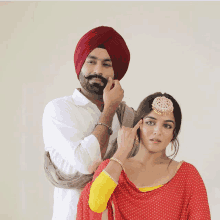 a man in a turban touches the face of a woman in a red dress