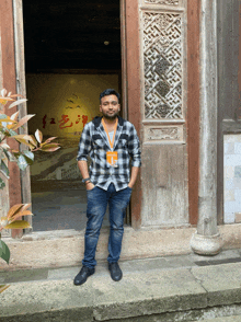 a man in a plaid shirt stands in front of a door that has chinese writing on it