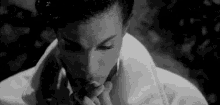 a black and white photo of prince smoking a cigarette in a bathrobe .