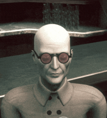 a bald man wearing round glasses stands in front of a shelf of glasses