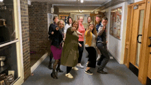 a group of people posing for a picture in a hallway with a sign on the wall that says " welcome "