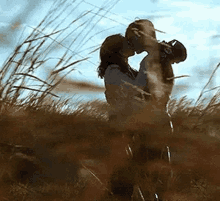 a man and a woman are kissing in a field .