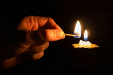 a person is lighting a candle with a match in the dark