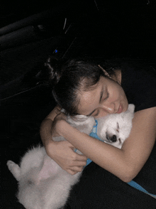 a woman is sleeping with a small white dog