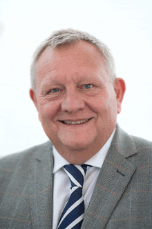 an older man in a suit and tie smiles for the camera