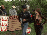 a man in a cowboy hat stands next to a woman in front of a stack of boxes of cherries