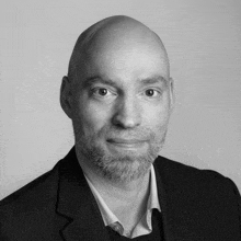 a bald man with a beard wearing a suit and white shirt