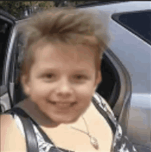 a young girl is sitting in the back seat of a car smiling .