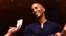 a man in a black shirt is laughing while someone holds a piece of paper in front of him