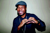 a man wearing a hat and a polka dot shirt makes a heart shape with his hands