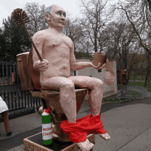 a statue of a man sitting on a toilet holding a toilet brush