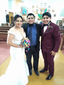 a bride and groom pose for a photo with a man in a suit