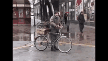 a man riding a bike on a wet street in front of a store that has a sign that says do not enter