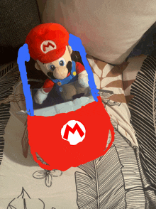 a stuffed mario sitting in a red car with a white m on it