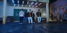 a group of young men are dancing in front of a wall that has the word peace painted on it