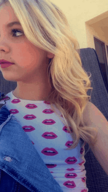 a girl with blonde hair wearing a white top with pink lips on it