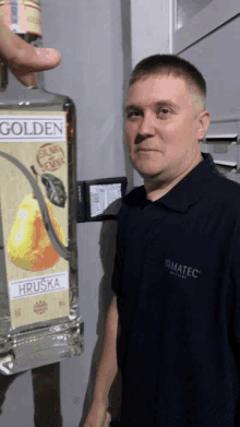 a man standing next to a bottle of golden hruska vodka