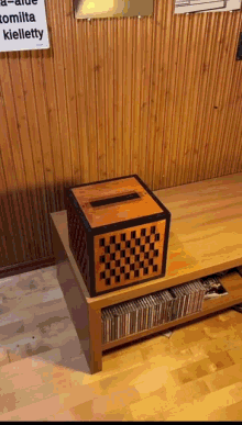 a wooden box with a checkered pattern sits on a wooden table in front of a sign that says kielletty