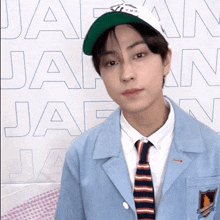 a young man wearing a hat and tie is standing in front of a wall with the word japan on it