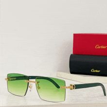 a pair of green cartier sunglasses sit on a shelf