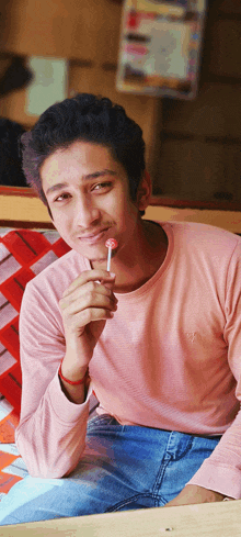 a man in a pink shirt is holding a lollipop