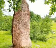 a large stone in the middle of a grassy field has a drawing on it that says ' a ' on it