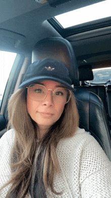 a woman wearing glasses and a black hat is sitting in the back seat of a car