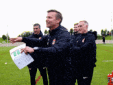 a group of men are standing on a field and one man is holding a piece of paper that says ' a ' on it