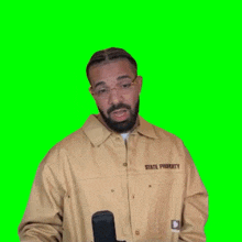 a man with a beard and glasses is standing in front of a green screen .