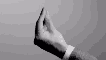 a black and white photo of a man 's hand in a suit giving the middle finger