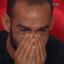 a man with a beard is covering his face with his hands and crying