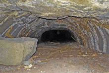 a dark cave filled with rocks and dirt with a rock in the middle of it .