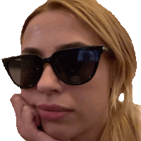 a woman wearing sunglasses has her hand on her chin .