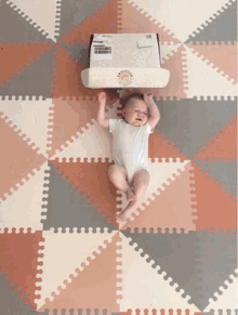 a baby is laying on a puzzle mat with a box on top of it that says ' baby ' on it