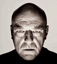 a close up of a man 's face with a serious look on his face and a bald head .