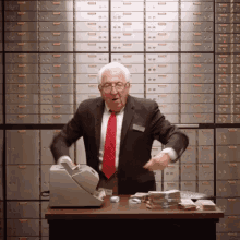 a man in a suit and tie is standing in front of a cash register with a bunch of money on it