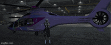 a woman is standing next to a purple helicopter that says ambulance on it