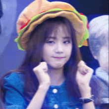 a girl wearing a hat that looks like a hamburger is making a face