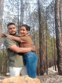 a man and a woman pose for a picture in the woods